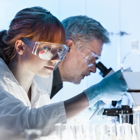 Scientists in a laboratory conducting skincare research, wearing protective eyewear and gloves while analyzing samples to develop advanced anti-ageing formulations.