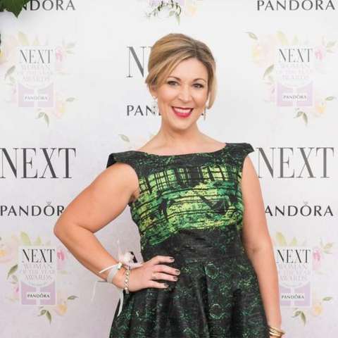 Rachael D'Aguiar in a black and green patterned dress posing on the red carpet at the Next Woman of the Year Awards, sponsored by Pandora